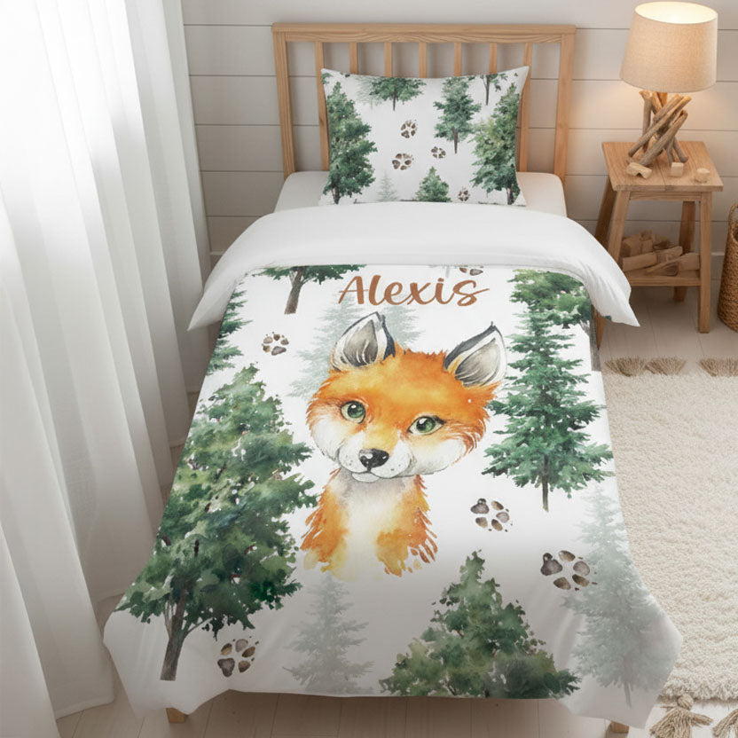 Literie lit simple pour enfant personnalisée à vue d'oiseau style Pinterest. Housse de couette et taie d'oreiller blanches à motif forêt, renard aquarelle et empreintes d'animaux. Prénom de l'enfant ou du bébé imprimé dans la literie. Décor de chambre d'enfant bois et blanc lumineux