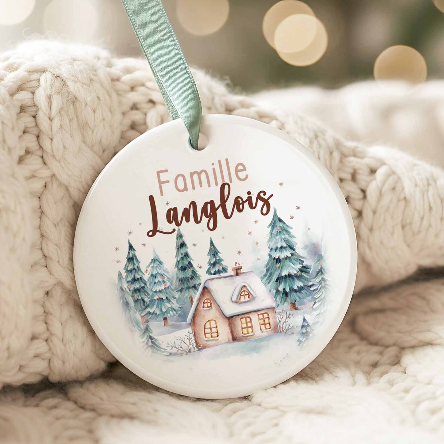 Ornement de Noël en céramique avec maison hivernale aquarelle, forêt enneigée et personnalisation du nom de famille